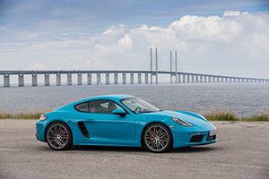 Porsche 718 Cayman miamiblau in Schweden vor Brücke übers Meer geparkt