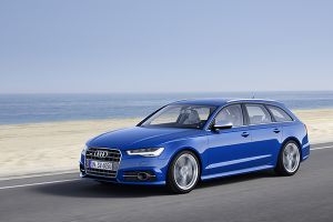 Blauer Audi S6 Avant fahrend am Meer, Sandstrand schräg links vorne