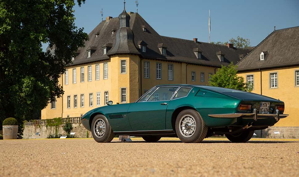 Dunkeltürkiser Maserati Ghibli parkt vor Schloss Dyck