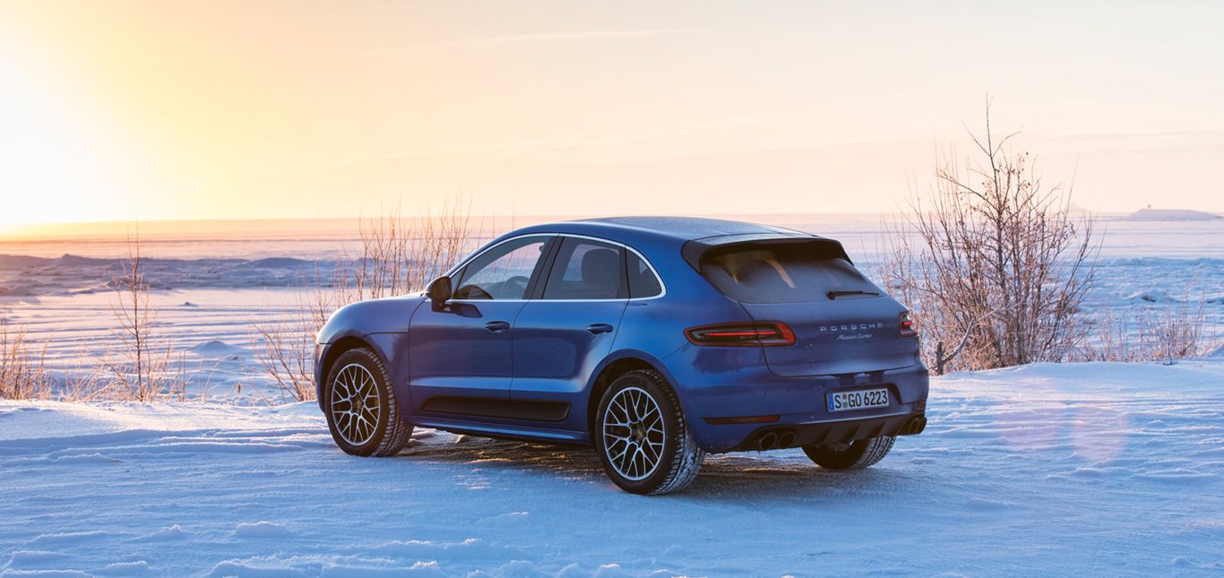Seitenansicht eines Porsche Macan vor einer Winterlandschaft.
