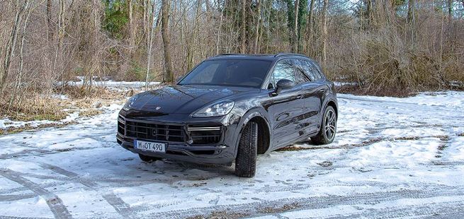 Schwarzer Porsche Cayenne Turbo auf verschneitem Seeparkplatz
