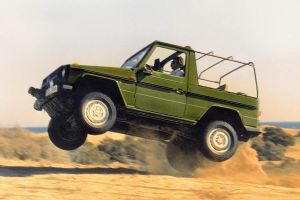 Olivgrüne Mercedes G-Klasse springt in Dünensand