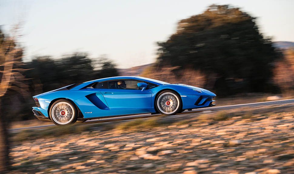 Blauer Lamborghini Aventador fährt auf Landstraße von der rechten Seite
